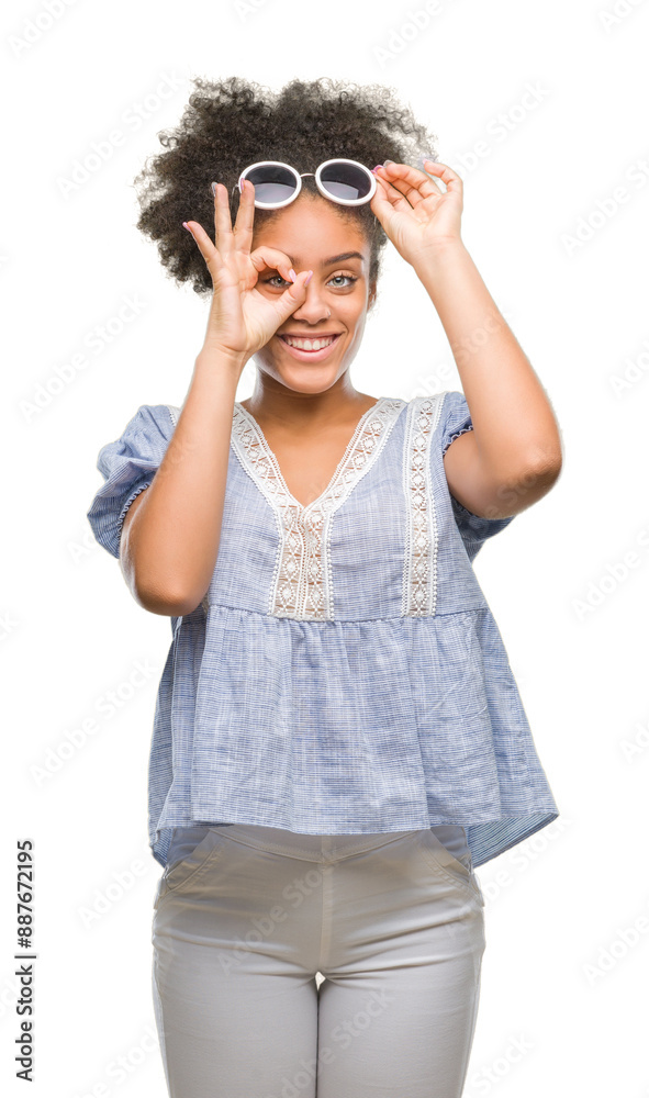 Sticker Young afro american woman wearing glasses over isolated background doing ok gesture with hand smiling, eye looking through fingers with happy face.