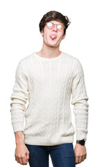 Obraz premium Young handsome man wearing glasses over isolated background sticking tongue out happy with funny expression. Emotion concept.