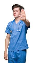 Young doctor wearing medical uniform over isolated background doing stop sing with palm of the...
