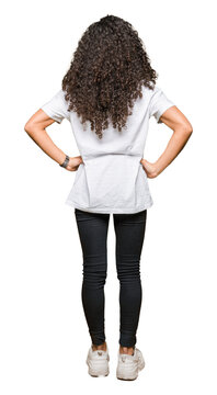 Young beautiful woman with curly hair wearing white t-shirt standing backwards looking away with arms on body