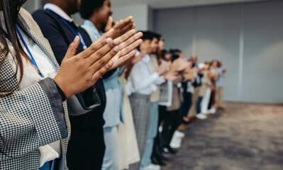 Colleagues applaud at business conference presentation in workplace setting