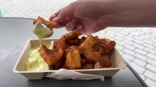 Kibbeling dipping in sauce, Dutch snack of fried cod fish served on tray. Popular national street food in the Netherlands.