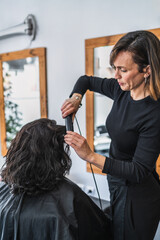 Naklejka premium Hairdresser Straightening Client's Hair in a Modern Salon Setting
