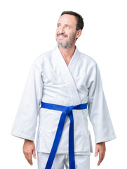 Handsome middle age senior man wearing kimono uniform over isolated background smiling looking side and staring away thinking.