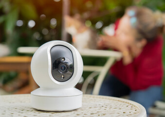 Close-up of security camera standing with cat and owner relaxing in the garden.