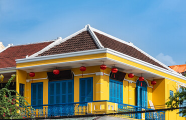 Classic style house yellow walls, wooden blue door and windows in old town Hoi An. Top of the house.
