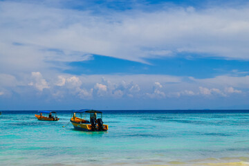 Aerial view of Perhentian Islands beach with boats docked near a wooden pier and lush greenery