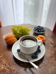 Breakfast in bed. Cup of coffee with fresh fruits on a wooden table in a hotel room.