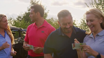 Mature and mid adult couples standing by golf buggy checking score cards together -= shot in slow motion