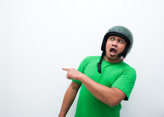 A man wearing motorcycle helmet smiling and pointing beside him
