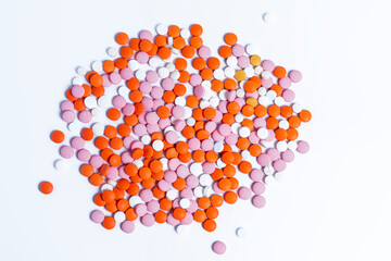 Pile of multicolored round pills on white background.