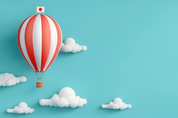 Fototapeta premium A red and white striped hot air balloon with the flag of Japan rises into a clear blue sky, surrounded by fluffy white clouds.