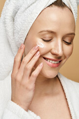 A gorgeous woman exudes natural beauty as she smiles with a towel wrapped around her head.