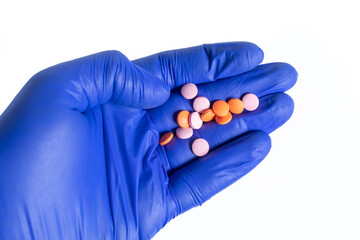 Closeup of gloved hand holding lots of pink and orange pills