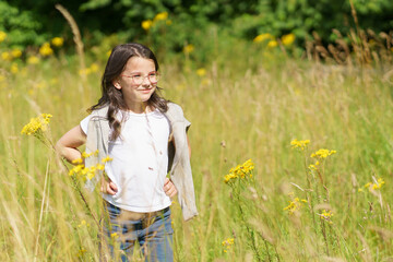 A little teenage girl wearing glasses, jeans, a T-shirt and a sweater thrown over her shoulders...