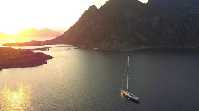 Sailboat at sunset, Lofoten, northern Norway, midnight sun, orange sky, high moutains and deep fjords. Rotating camera view