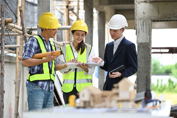 Engineers in safety helmet collaborating and sharing ideas, with construction pillars in the background
