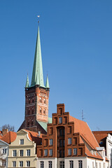 Turm der Kirche St. Petri in Lübeck, Deutschland, der neben den Giebeln alter Häuser emporragt