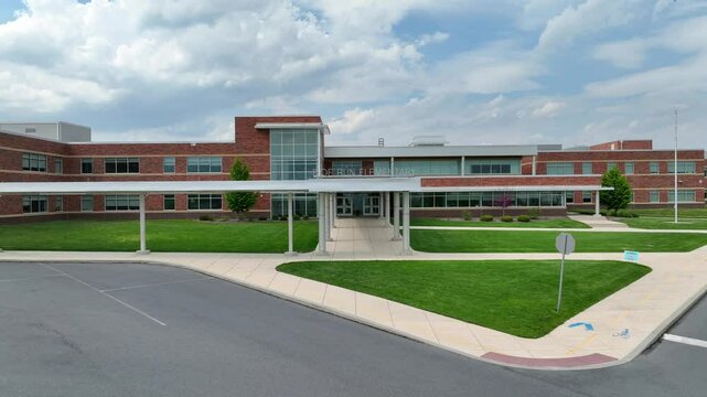 Aerial backwards shot closed doe run elementary school in America. Clouds and empty street in School district with clouds in spring.