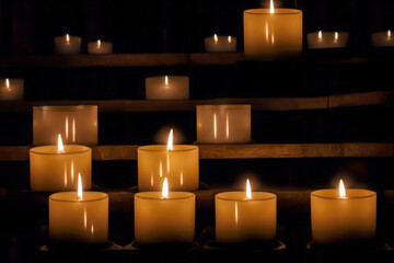 A collection of lit candles glowing warmly in a dark room, creating a serene and peaceful atmosphere, perfect for meditation or remembrance.