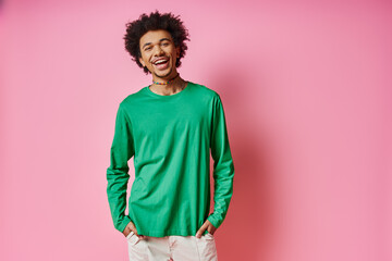A cheerful young African American man in casual wear stands in front of a pink wall, showcasing his emotions. © LIGHTFIELD STUDIOS