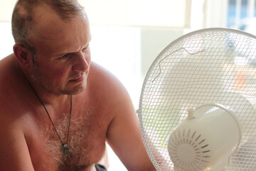 Naklejka premium A man carefully looks at how to repair an air conditioner for cooling air in the summer