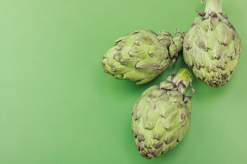 Fototapeta premium Fresh globe artichoke cooking on a green background. Traditional seasonal ingredients