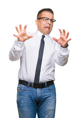 Middle age bussines arab man wearing glasses over isolated background afraid and terrified with fear expression stop gesture with hands, shouting in shock. Panic concept.
