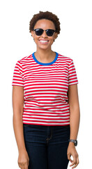 Beautiful young african american woman wearing sunglasses over isolated background with a happy and cool smile on face. Lucky person.