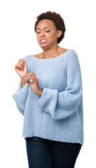 Young beautiful african american woman wearing a sweater over isolated background disgusted expression, displeased and fearful doing disgust face because aversion reaction. With hands raised