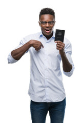 Young african american man holding australian passport with surprise face pointing finger to himself