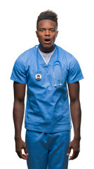 Fototapeta premium Young african american doctor man over isolated background wearing surgeon uniform afraid and shocked with surprise expression, fear and excited face.