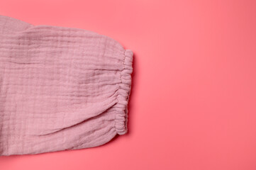 Texture of pink muslin fabric on pink background. Cotton textile and clothing. Soft delicate natural organic cotton fabric for sewing, needlework, baby towel, diaper, dress. Fabric background