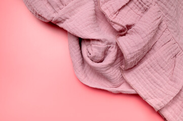 Texture of pink muslin fabric on pink background. Cotton textile and clothing. Soft delicate natural organic cotton fabric for sewing, needlework, baby towel, diaper, dress. Fabric background