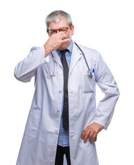 Handsome senior doctor man over isolated background smelling something stinky and disgusting, intolerable smell, holding breath with fingers on nose. Bad smells concept.