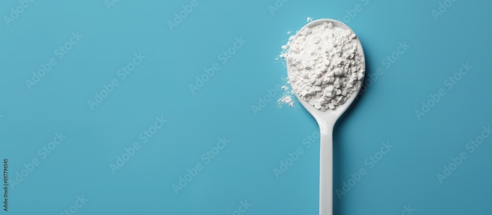 Poster White powder in a plastic spoon arranged on a blue background in a composition ideal for adding text suitable for display with copy space image