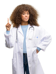 African american doctor woman, medical professional working happy and surprised cheering expressing wow gesture pointing up