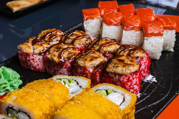 Japanese food: sushi and a variety of rolls on a black plate. Japanese restaurant menu, sushi delivery. Selected focus