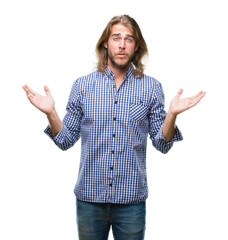 Young handsome man with long hair over isolated background clueless and confused expression with...