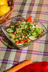 Fresh vegan salad on kitchen table with cucumber, letuce, tomato, jellow pepper and chick peas, top view, flat lay