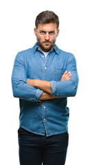 Young handsome man over isolated background skeptic and nervous, disapproving expression on face with crossed arms. Negative person.