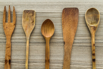 Set of wooden kitchen utensils including spoons, forks, and spatulas arranged neatly on a wooden surface.