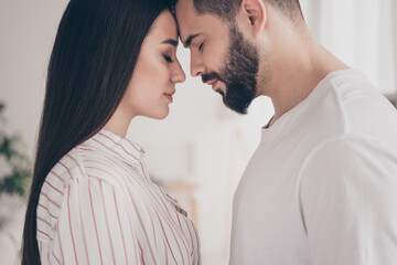 Photo of cheerful cute young couple enjoy weekend couple gentle touch forehead wife husband buy new apartment indoors inside house home