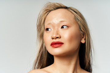 Naklejka premium An attractive Asian woman with long hair and red lipstick poses confidently in vibrant attire.