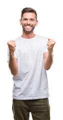 Fototapeta premium Young handsome man over isolated background very happy and excited doing winner gesture with arms raised, smiling and screaming for success. Celebration concept.