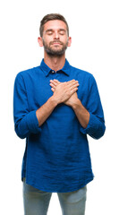 Young handsome man over isolated background smiling with hands on chest with closed eyes and grateful gesture on face. Health concept.