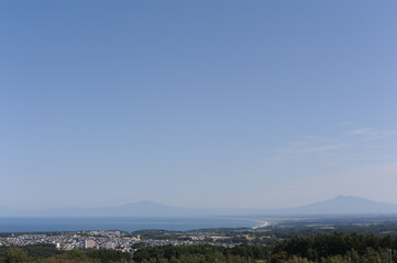 Panorama of Abashiri city with Mount Rausu and Mount Iō in the background on a sunny day with blue sky in summer, Hokkaido island, Japan