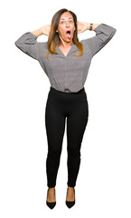 Fototapeta premium Beautiful middle age business woman Crazy and scared with hands on head, afraid and surprised of shock with open mouth