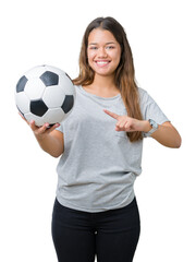 Young beautiful brunette woman holding soccer football ball over isolated background very happy pointing with hand and finger