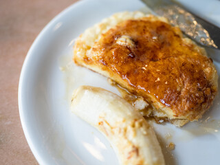 a plate of pancakes with powdered sugar and accompanied by banana slices and syrup